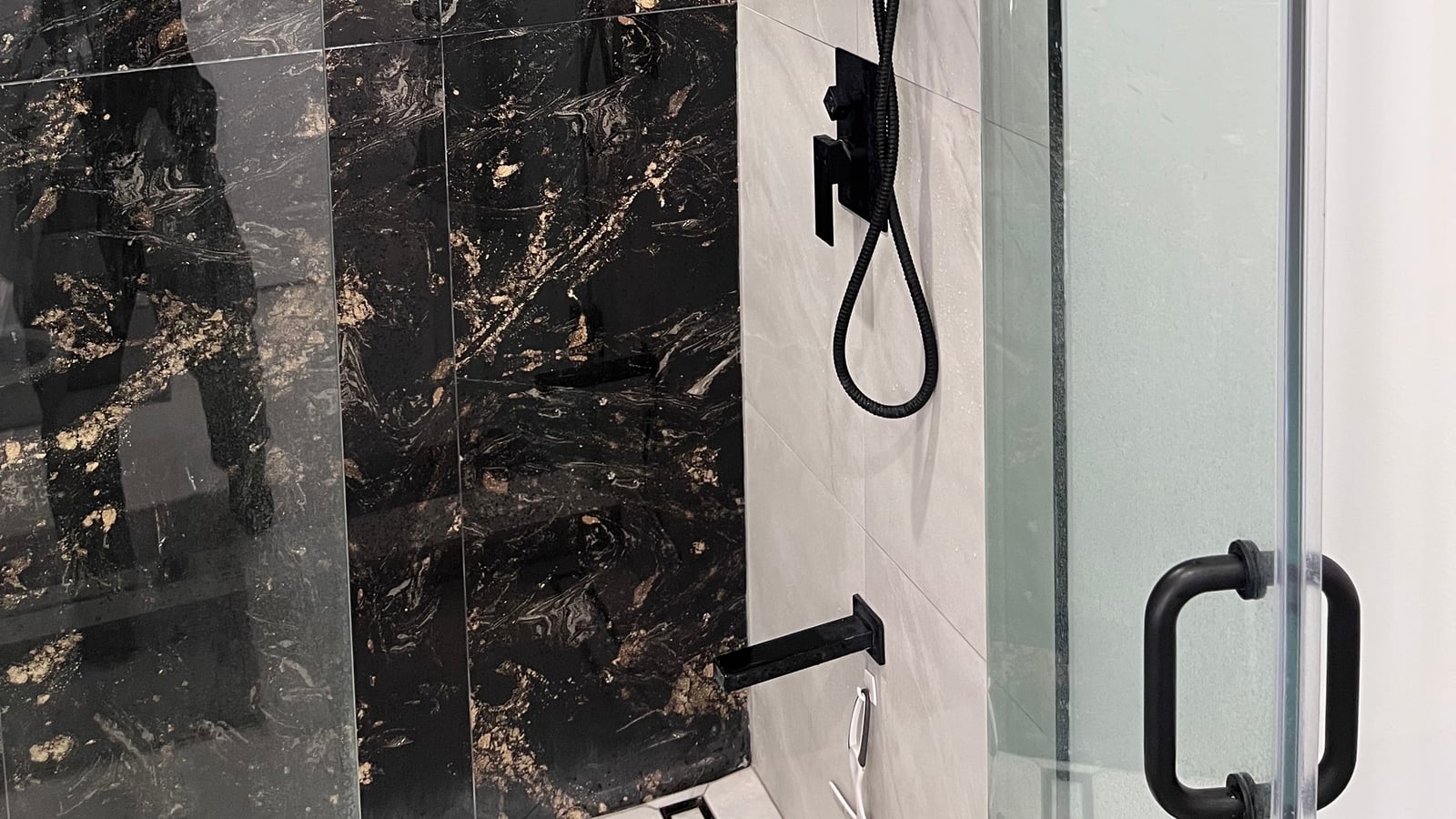 Shower with black marble-look porcelain walls, matte black fixtures and a rain head — a bathroom in Kitchener by the company