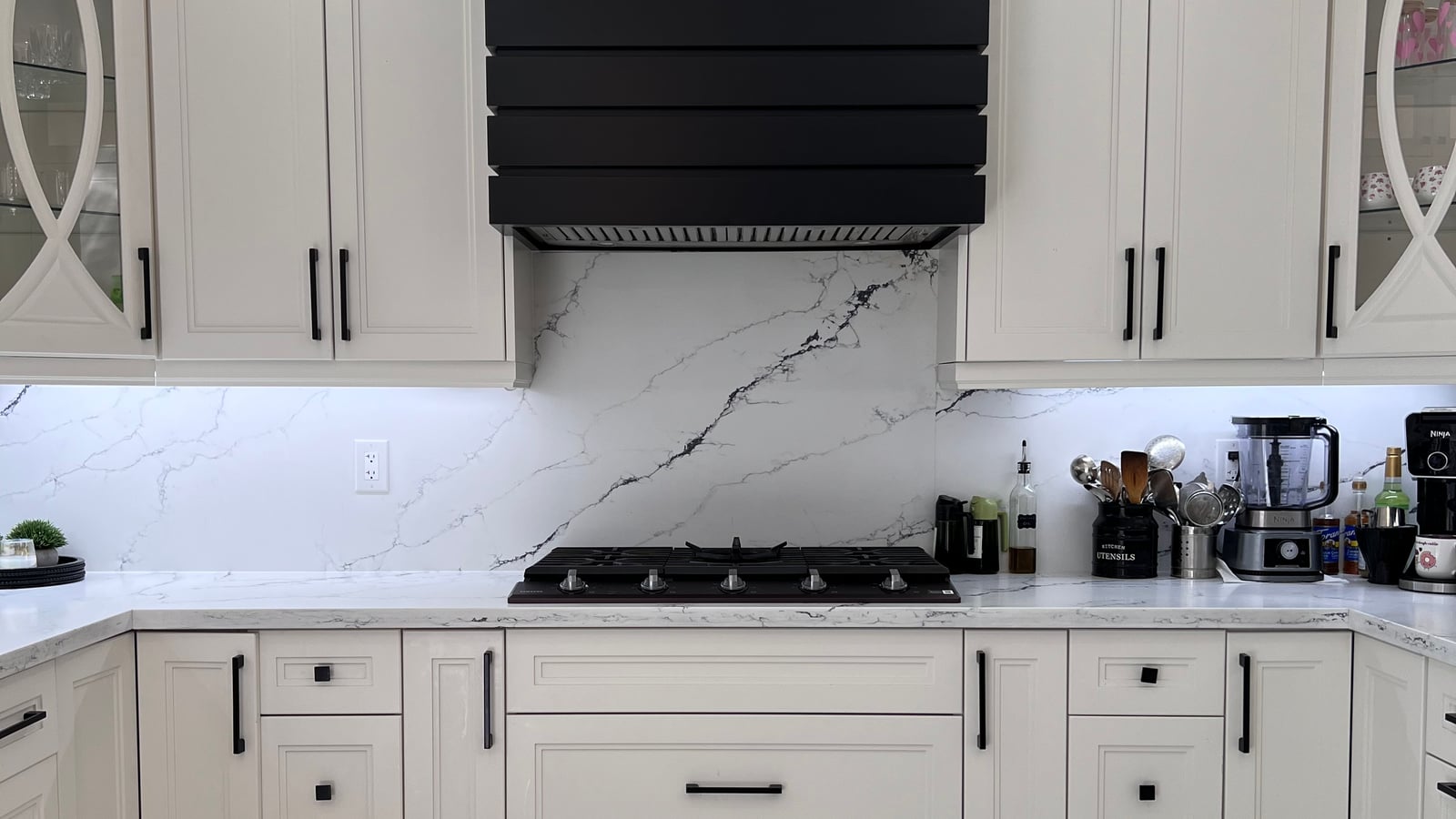 Cooktop under a decorative hood surround with backsplash and large-format tile flooring — a complete kitchen renovation from the October 2026 catalogue