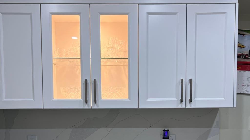 Illuminated glass-front upper cabinets over a marble-look quartz backsplash — kitchen cabinets manufactured by Prime Kitchen and Bath in Mississauga, from the company's own project photos
