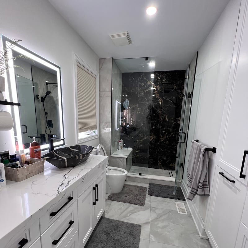 Bathroom with vanity cabinetry, lit mirrors and a glass shower enclosure