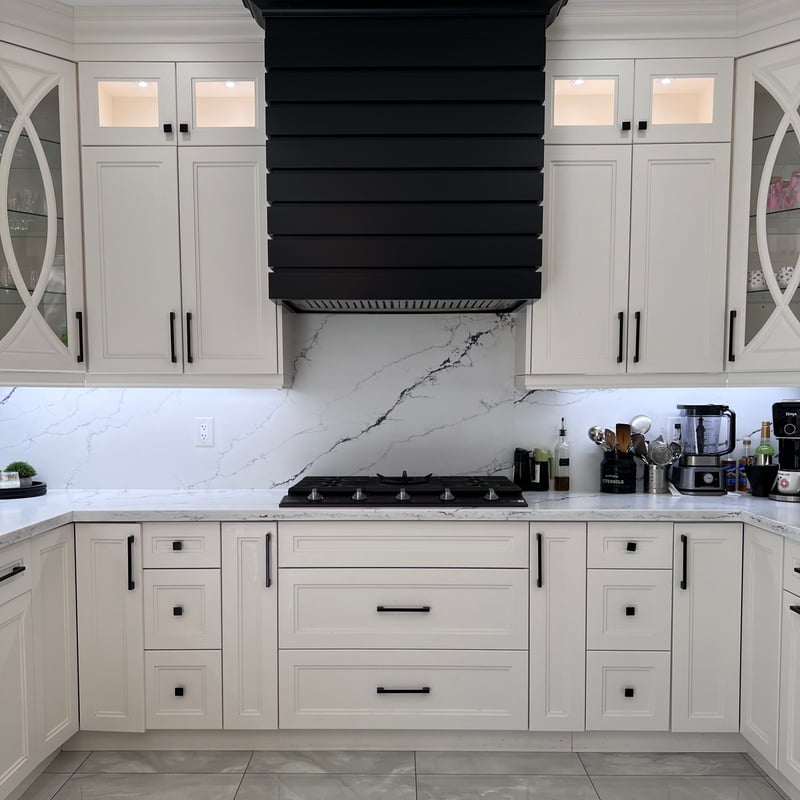 Same kitchen from the floor: cooktop under the hood surround, backsplash and large-format tile flooring