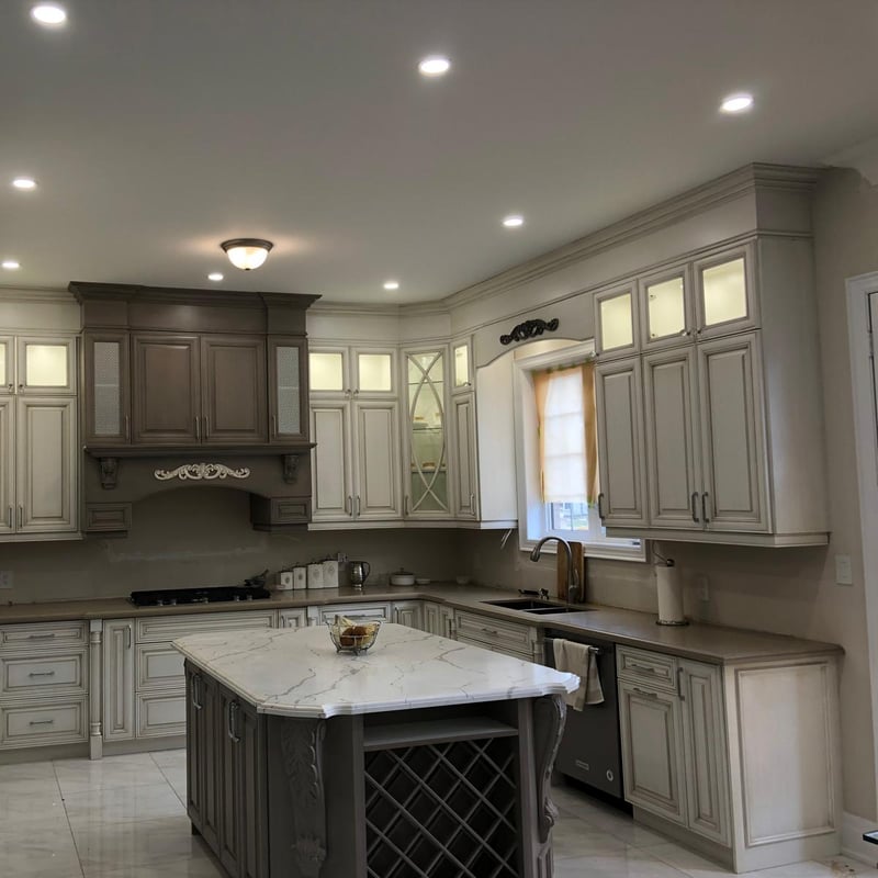 Traditional kitchen in a grey glazed finish with a carved hood and a large island with seating