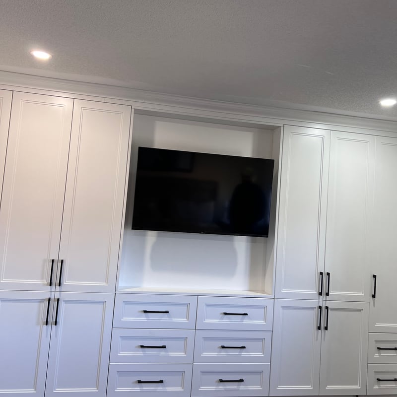 Entertainment unit with the TV mounted in a central recess surrounded by closed cabinets and drawers