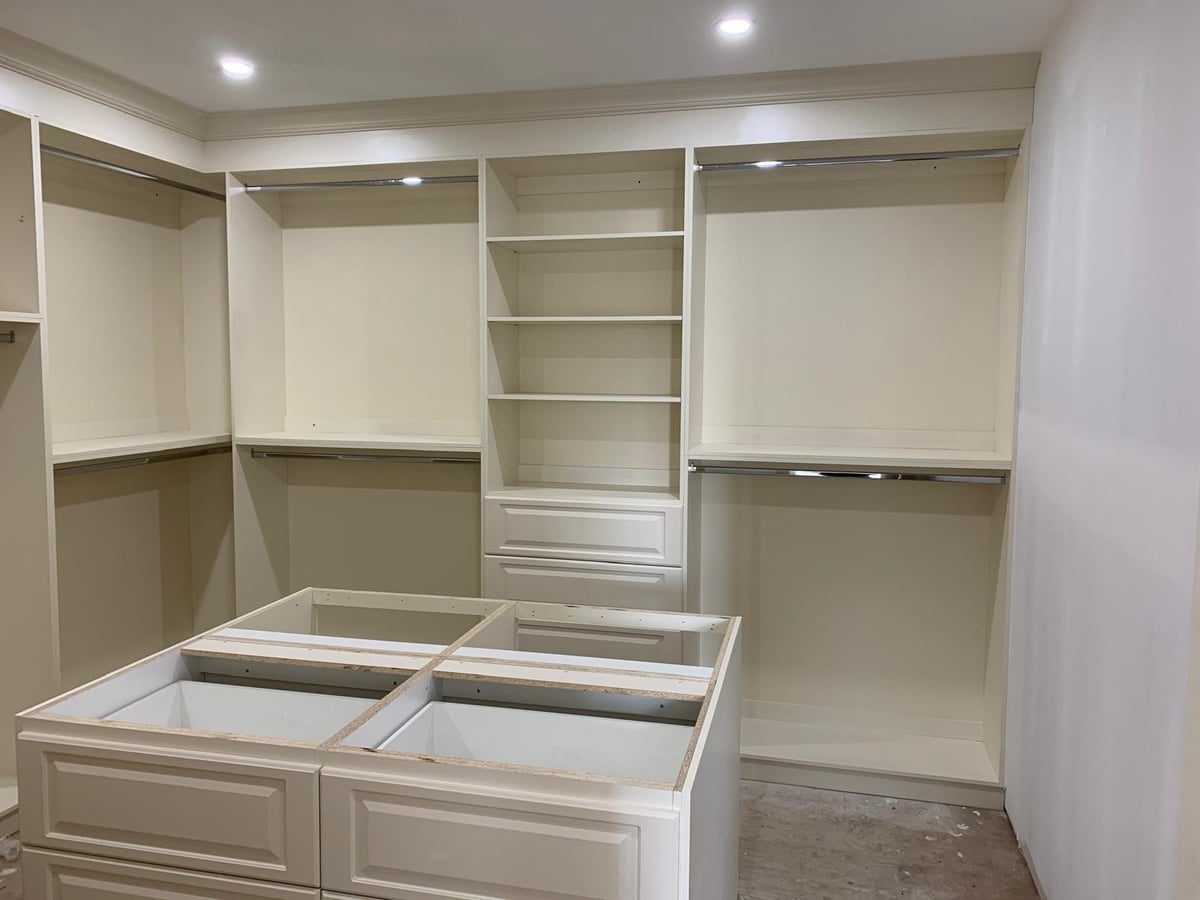 Walk-in closet with white shelving, a drawer bank and hanging sections