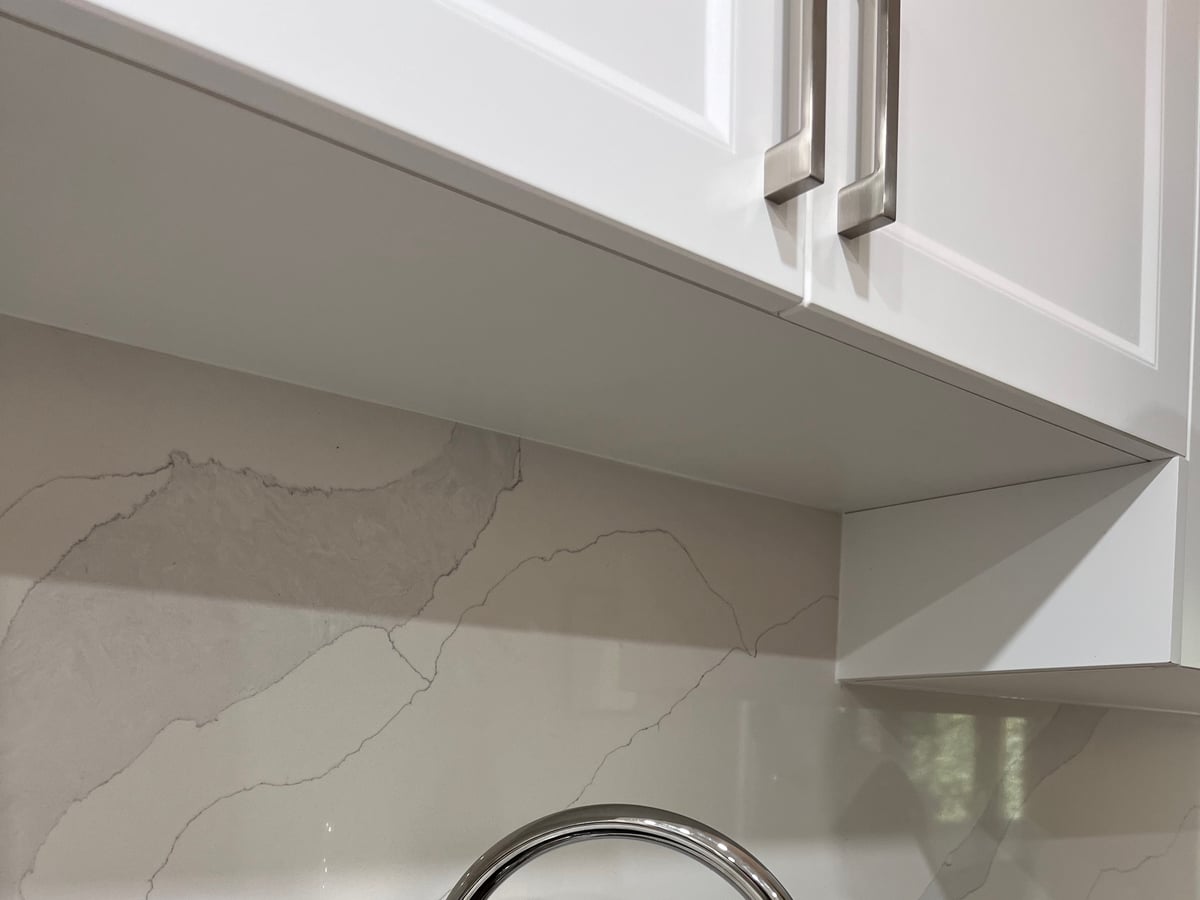 Marble-look quartz backsplash veining beside a chrome faucet