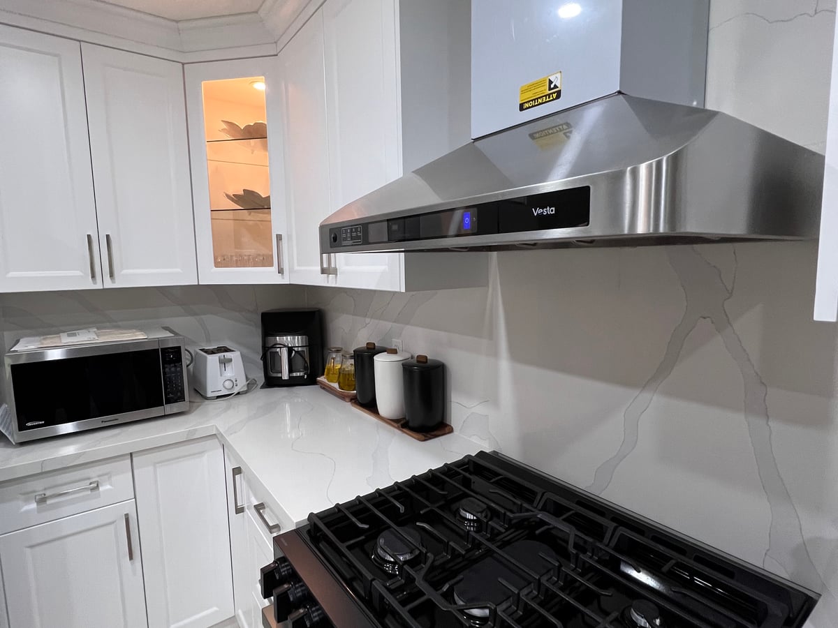 Stainless range hood between upper cabinets above a gas range