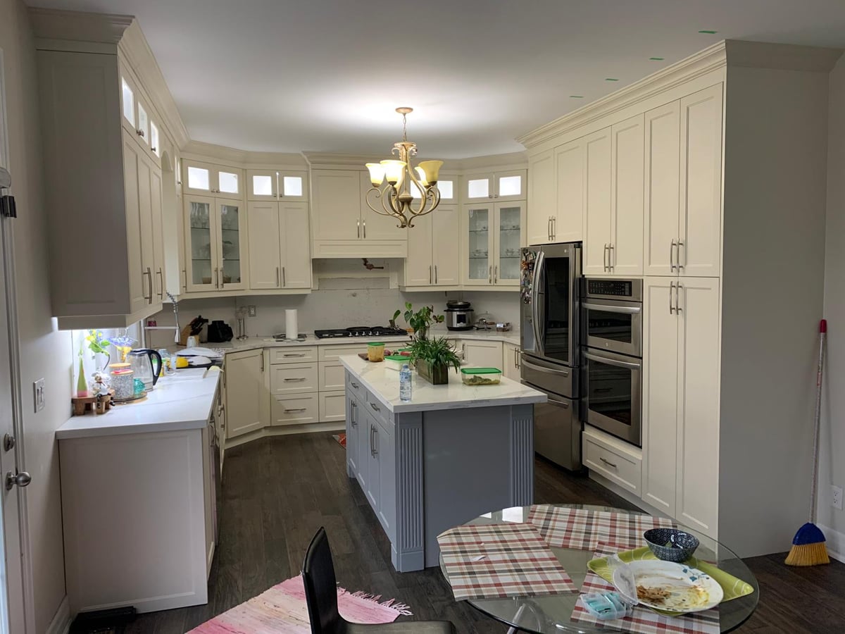 White kitchen with an island, a chandelier and built-in double wall ovens