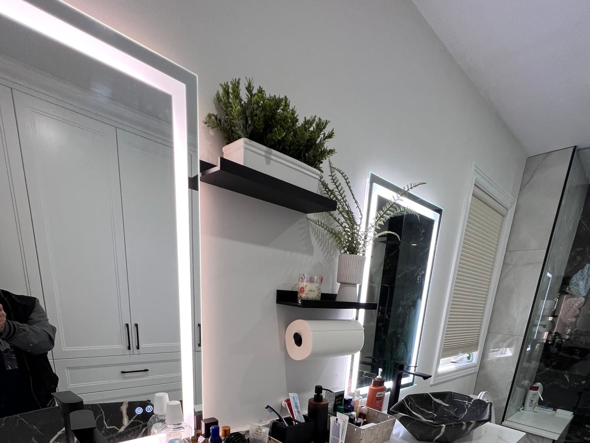 Bathroom vanity with a black-veined stone countertop, vessel basin and lit mirror