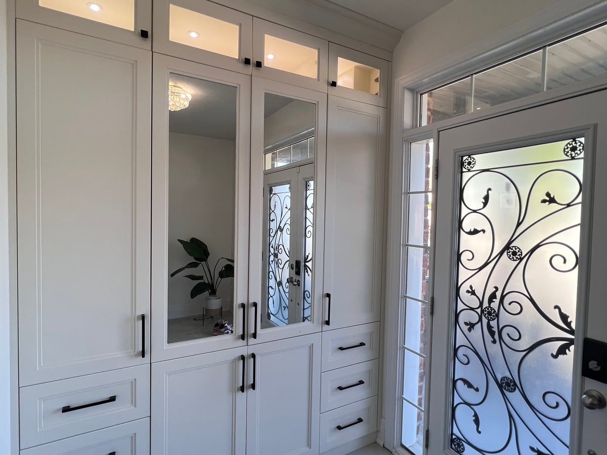 Entry built-in with glass doors beside a front door with decorative ironwork