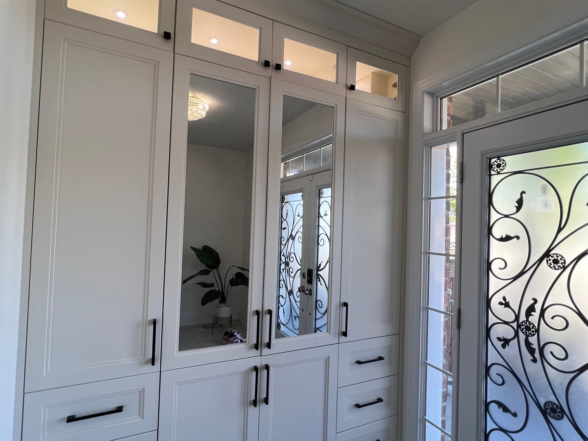 Entry closet with mirrored doors, drawers and lit glass display compartments