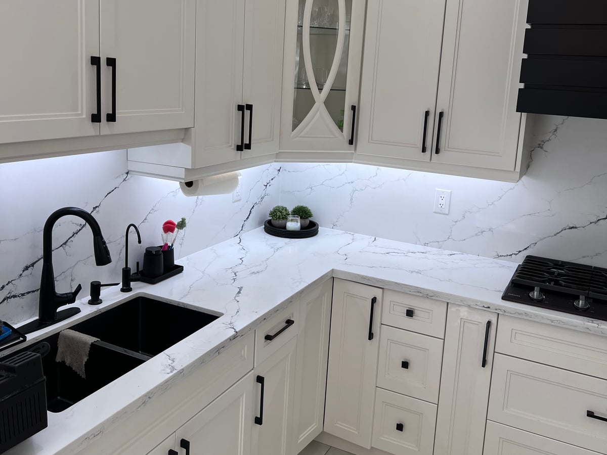 Matte black faucet over an undermount sink set in a veined quartz countertop