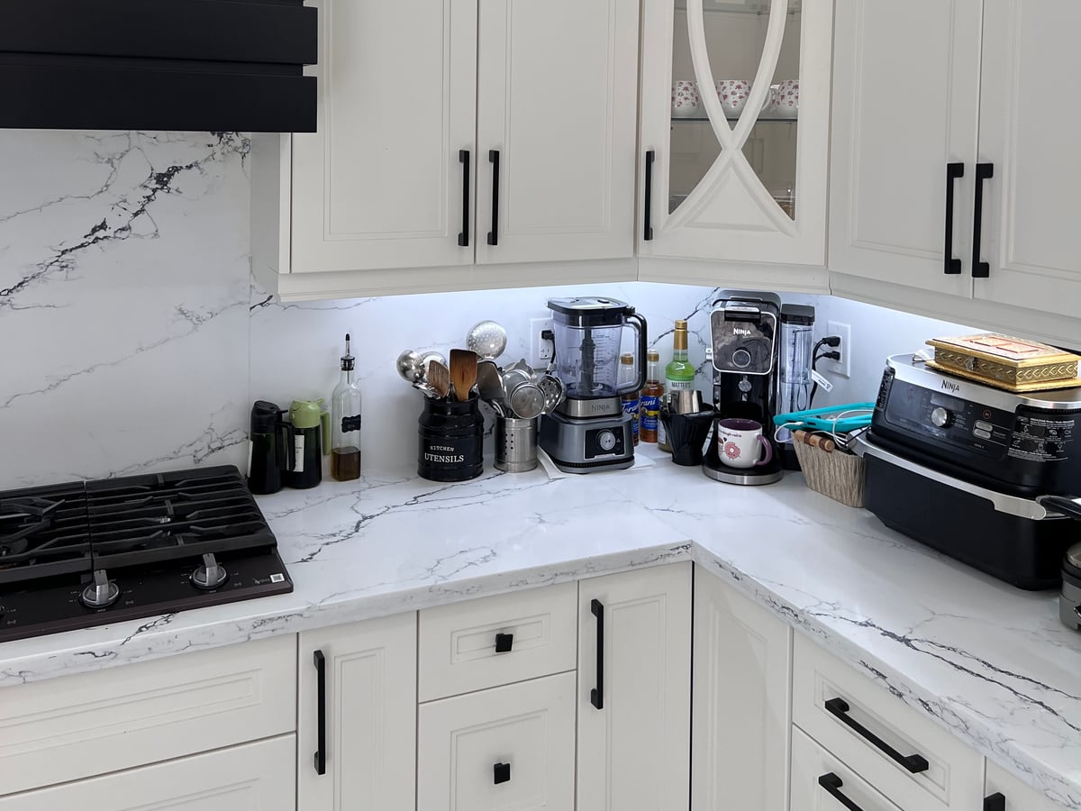 Upper cabinets with decorative mullion glass doors and lit interiors above the counter