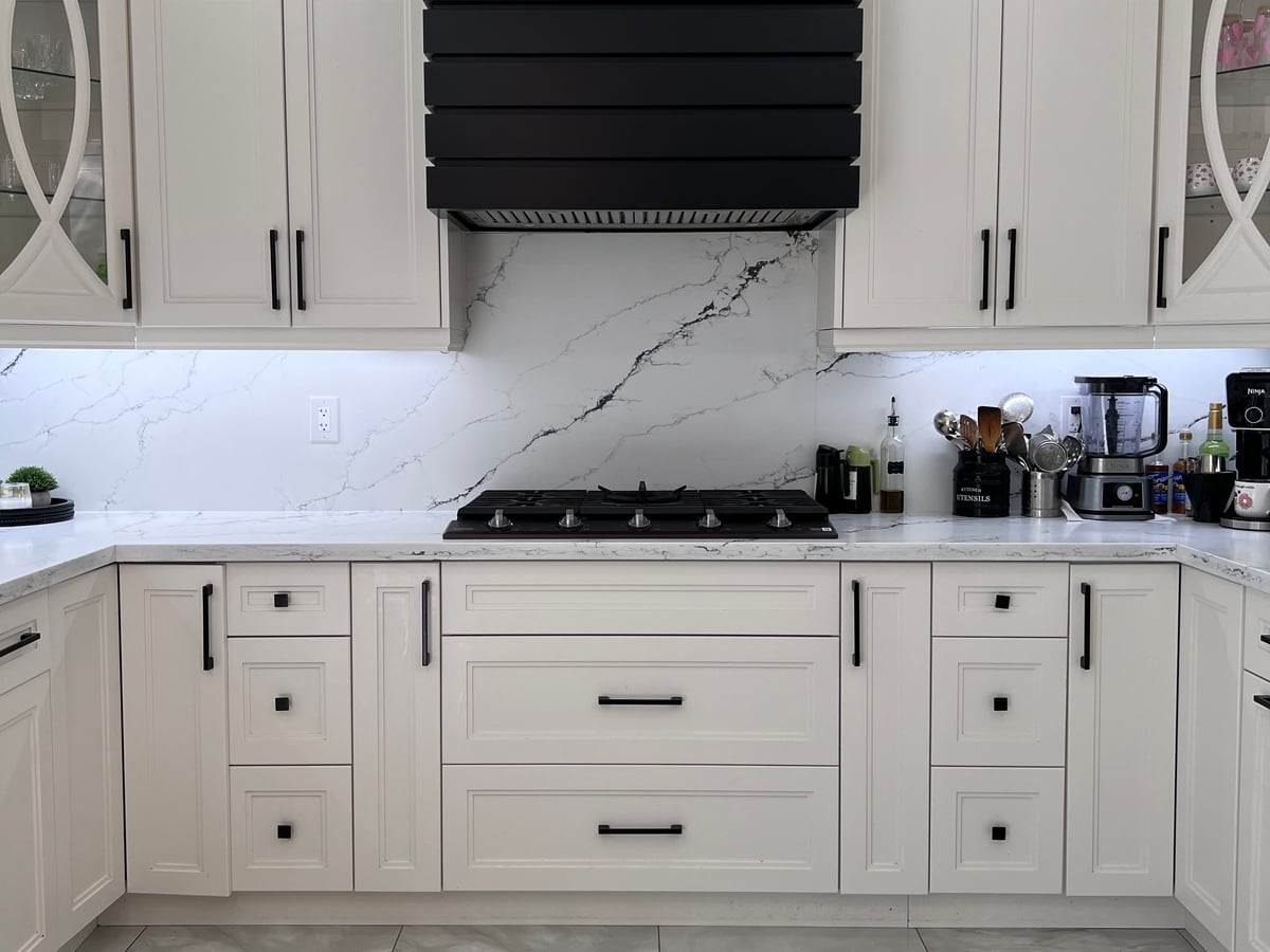 The kitchen seen from the floor: cooktop, hood surround and large-format tile flooring