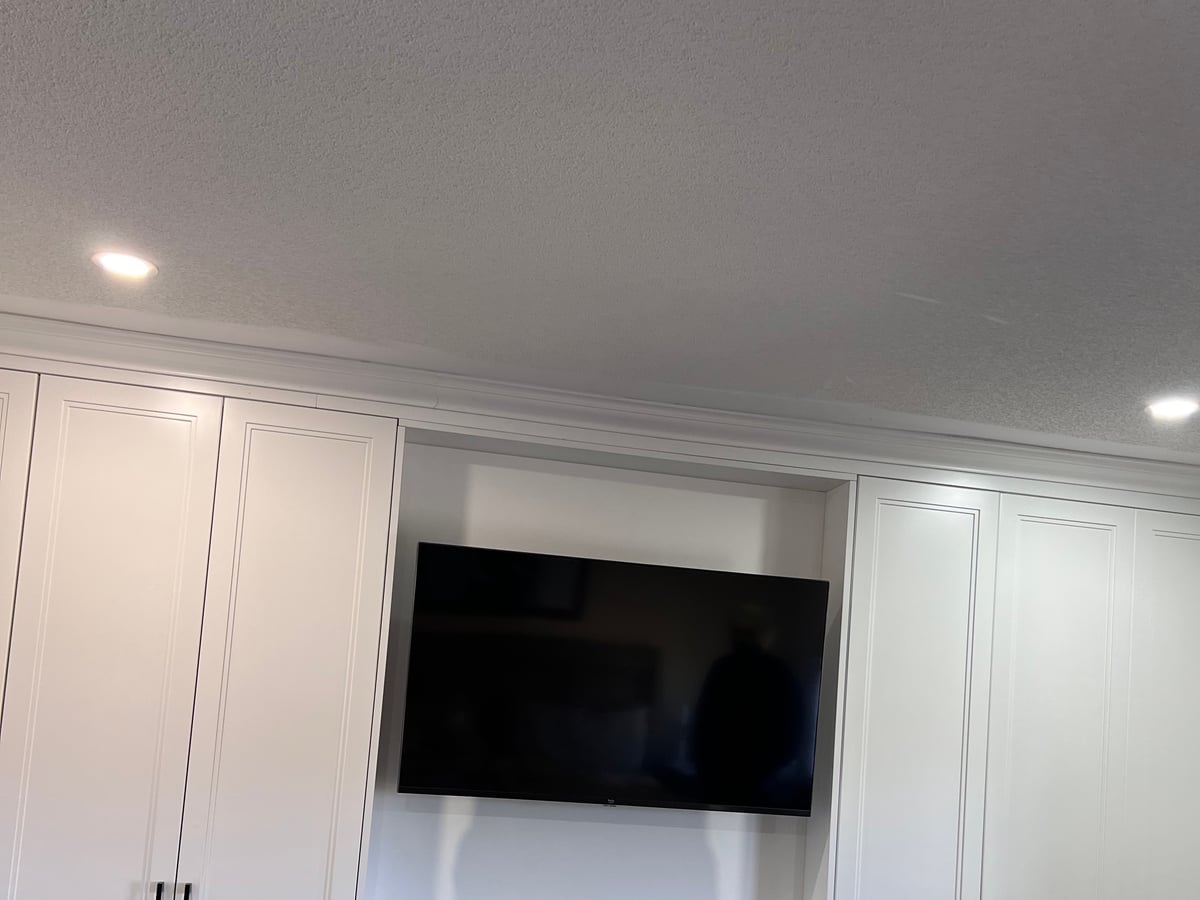 Media wall with the television set into a recess surrounded by white cabinets