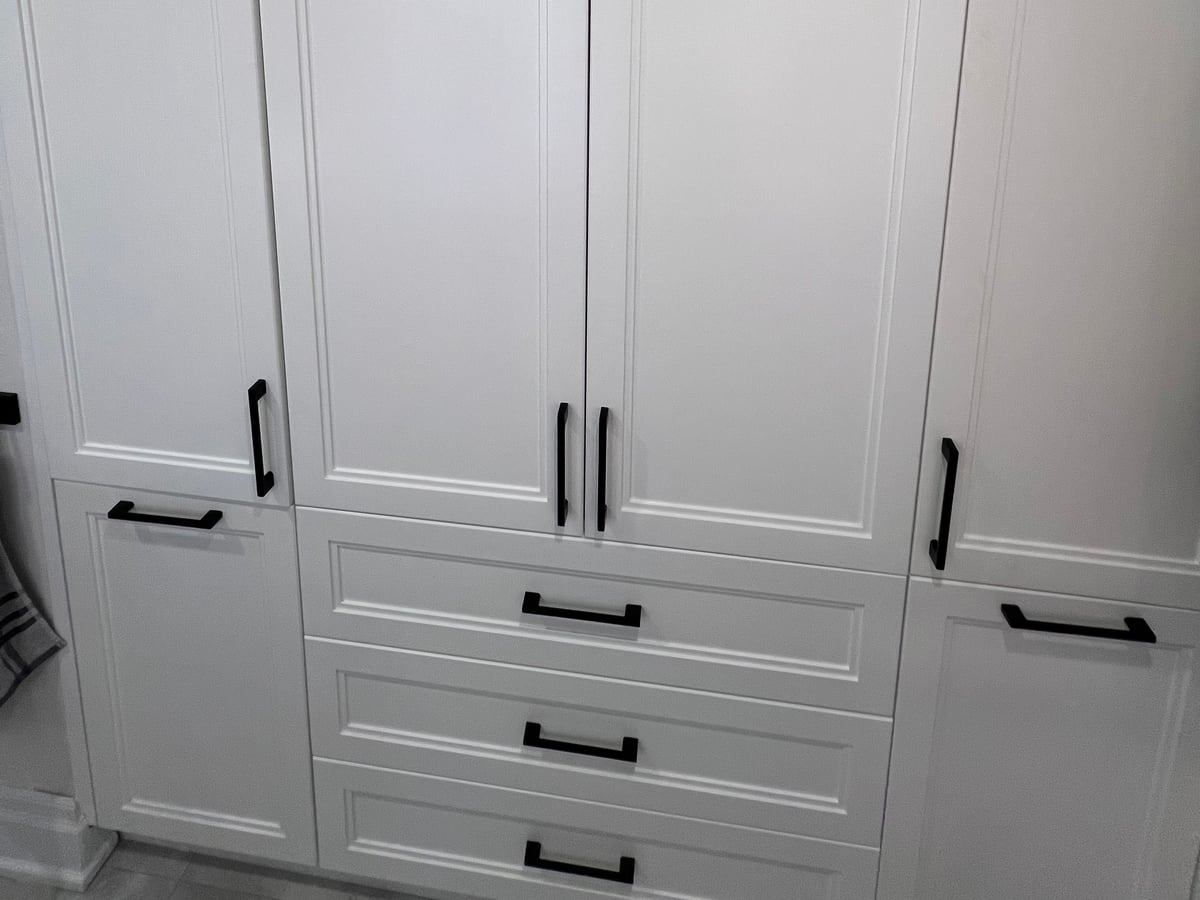 Full-height white closed cabinetry with a central drawer stack